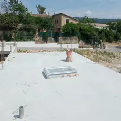 Chantier de construction avec dalle béton fraîchement coulée. Sac de ciment à proximité, peut-être pour estimer le prix dalle béton m2.