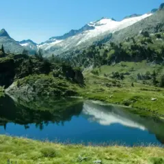 Reflejo de montañas nevadas en los ibones de Villamuerta, un paisaje alpino sereno.