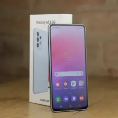 Jasnoniebieski Samsung A53 5G, model z 2022 roku, obok swojego pudełka. Ekran pokazuje pogodę i ikony aplikacji.
