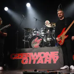 Czerwone gitary na scenie, jak jesienny deszcz dźwięków. Zespół gra, a na tle logo zespołu.