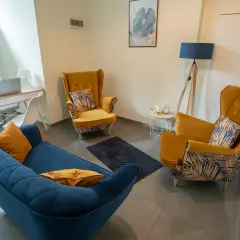 Wnętrze gabinetu psychologicznego z kanapą i fotelami w kolorach niebieskim i żółtym.