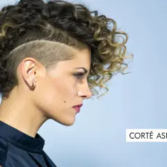 Mujer con pelo corto rizado juvenil, rapado a los lados y con volumen arriba. Un corte asimétrico que resalta su estilo audaz.