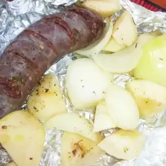 Kaszanka z grilla z cebulą w folii aluminiowej, gotowa do pieczenia. Aromatyczne dodatki podkreślą smak.