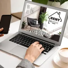 Szukasz mieszkania? Na co zwrócić uwagę przy wynajmie? Laptop pokazuje ofertę, a telefon jest pod ręką.