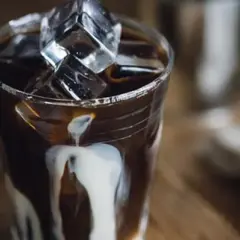 Ett glas med is och mörk, stark kaffe där grädde virvlar ner. En perfekt vietnamesisk iskaffe för en varm dag.