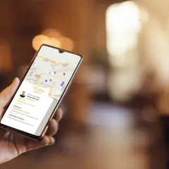 Dłoń trzyma smartfon z mapą i danymi firmy. Czy wizytówka Google jest płatna? Nie, jest darmowa, co widać na ekranie.