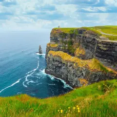 Skały w Irlandii, zielone wzgórza i błękitne morze. Przyjemna irlandia temperatura sprzyja spacerom po klifach.