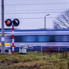 Pędzący pociąg mija przejazd kolejowy z czerwonymi światłami, zgodnie z nowym rozporządzeniem o przejazdach kolejowych.