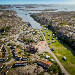 Vacker vy över Solvik first camp med stugor, husvagnar och lekplats vid havet.