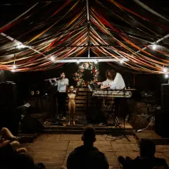Muzycy grają na scenie pod kolorowymi wstążkami. Atmosfera jak na **grajdół festiwal**.