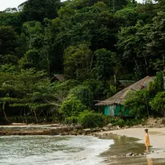 Dziewczynka w żółtej sukience na plaży w Tajlandii, myśląca o szczepieniach przed podróżą.