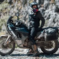 Motociclista con equipo **waterproof** listo para la aventura. ¿Será **Gore-Tex**? La moto, su compañera en terrenos difíciles.