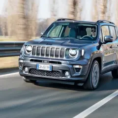 Ciemnoszary Jeep Renegade Hybrid jedzie po drodze, za kierownicą siedzi mężczyzna w okularach.