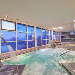 Piscina interior con ventanas azules que reflejan el cielo, cascadas y chorros de agua. Un lugar perfecto para relajarse, como si estuvieras en un spa de tui blue los gigantes.