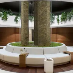 Nowoczesne wnętrze spa z okrągłą sofą, roślinnością i drewnianymi panelami.