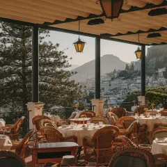 Terrazza con tavoli apparecchiati e vista su Taormina. Un luogo perfetto per un aperitivo al bar Timeo Taormina.