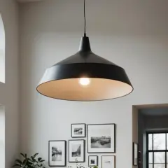 Czarna lampa w stylu industrialnym zwisa z wysokiego sufitu, oświetlając wnętrze z dużymi oknami i galerią czarno-białych zdjęć na ścianie.