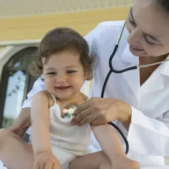Medico ascolta il cuore di un bambino con uno stetoscopio. Un soffio al cuore cos'è? La visita medica rassicura.
