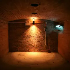Interior de sótano de ladrillo con luz cálida y una lámpara fluorescente.