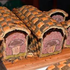 Pâté en croûte d'origine, décoré d'un champignon stylisé. Une œuvre culinaire qui raconte l'histoire de ce plat traditionnel.