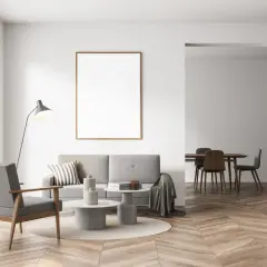Nowoczesny salon z szarą kanapą i fotelem, stolikami kawowymi, lampą i pustą ramą na ścianie. Czy szary z beżem pasuje? Tak, tworzy przytulną atmosferę.