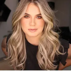 Frauenporträt mit welligem, blondem Haar und face framing highlights.