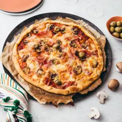 Une délicieuse pizza reine, garnie de jambon, champignons et olives, prête à être dégustée.