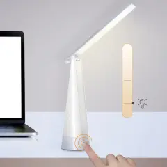 Biała lampka biurkowa z regulacją jasności, obok laptopa. Idealna do czytania, ile lumenów potrzebujesz?