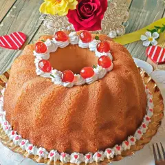 Un delicioso baba postre decorado con crema batida y cerezas rojas, listo para celebrar el amor.