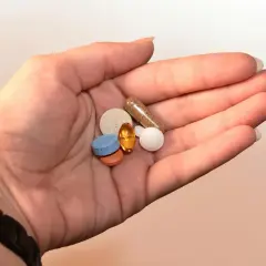 Dłoń trzyma garść tabletek i kapsułek. Czy to leki na zespół serotoninowy objawy?