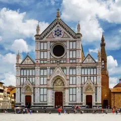 La magnifica facciata della Basilica di Santa Croce domina la piazza, con il cielo azzurro e nuvole bianche.