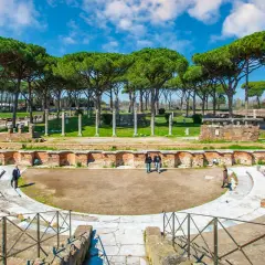 Antico teatro romano a Ostia Antica, Roma, con pini marittimi che incorniciano le rovine.