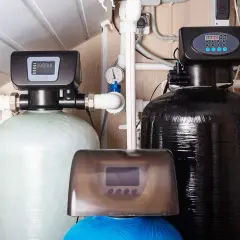 Système d'adoucisseur d'eau avec deux réservoirs, un clair et un noir, et un panneau de contrôle numérique. Un adoucisseur ballon eau chaude pour une eau plus douce.