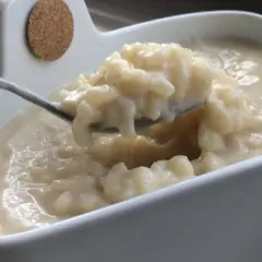 Cuillère prélevant une portion crémeuse de riz au lait dans un bol blanc.