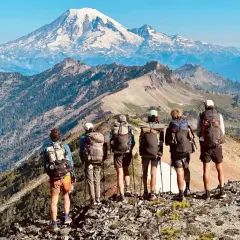 Sześcioro turystów z plecakami na grani, podziwiających majestatyczny szczyt. Przygoda na Pacific Crest Trail trwa.