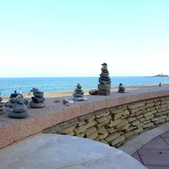 Torres de piedras en el **carboneras paseo marítimo**. El mar azul y el cielo despejado crean un fondo sereno para estas esculturas efímeras.