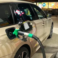 Tankowanie samochodu, zielony pistolet paliwa wlewa się do baku. Obawy o złej jakości paliwo diesel objawy mogą pojawić się po takiej wizycie na stacji.