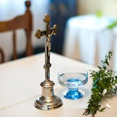 Krzyż, kropielnica z wodą i gałązka symbolizują tradycyjne błogosławieństwo.