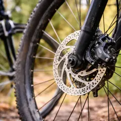 Zbliżenie na rowerową tarczę hamulcową i zacisk, gotowe do wymiany klocków hamulcowych.