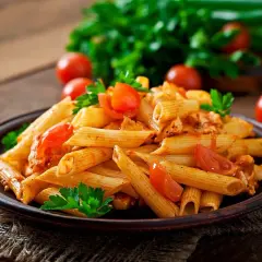 Penne z sosem pomidorowym i kurczakiem, ozdobione pomidorkami i natką pietruszki. Idealne pytanie: jakie wino do spaghetti?