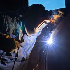 Spawacz w masce ochronnej spawa rurę, używając elektrody. Zastanawiasz się, jaka elektroda do stali 2mm?