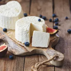 Formaggi freschi su tagliere rustico con fichi e mirtilli. La ricotta, pur essendo un latticino, contiene lattosio.