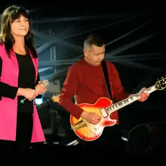 Kobieta z mikrofonem i mężczyzna grający na gitarze, członkowie zespołu Breakout, na scenie.
