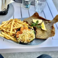 Pyszna ryba z frytkami i surówką na talerzu. Idealne miejsce, gdzie zjeść w Kołobrzegu, by poczuć smak Bałtyku.