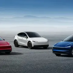 Trzy samochody Tesla: czerwony, biały i niebieski, stoją na pustkowiu.