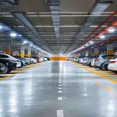 Rzędy samochodów na parkingu podziemnym, oświetlone jasnym, nowoczesnym oświetleniem.