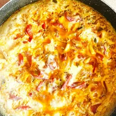 Pyszny omlet z warzywami w trakcie smażenia na patelni. Widoczne kawałki papryki i cebuli.