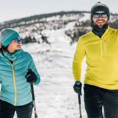 Para na nartach w górach. Ona w turkusowej kurtce, on w żółtej bluzie. Idealny strój w góry damski i męski na zimową przygodę.