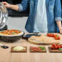 Gotowy przepis na pizzę: świeża pizza z pomidorkami i bazylią w piecyku, obok składniki: ser, wędlina, pomidorki.