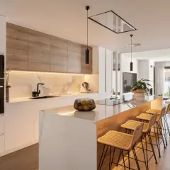 Cocina moderna con isla, encimera de mármol y lámpara barra led iluminando el espacio.